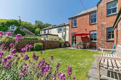 a garden with purple flowers and a brick building at 4 Bed in Padstow oc-p00297 in Padstow