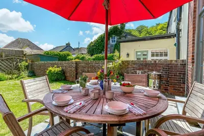 a wooden table with a red umbrella on a patio at 4 Bed in Padstow oc-p00297 in Padstow