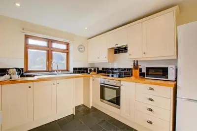 a kitchen with white cabinets and a sink and a microwave at 3 Bed in Padstow oc-p00281 in St Merryn