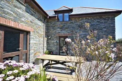 a wooden picnic table in front of a brick building at 3 Bed in Padstow oc-p00281 in St Merryn