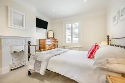 a white bedroom with a bed and a fireplace at 3 Bed in Padstow oc-p00329 in Padstow