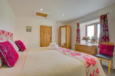 a bedroom with a large bed with pink pillows at 1 Bed in Padstow oc-p00288 in St Merryn