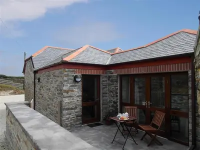 a stone house with a patio and a table at 1 Bed in Padstow oc-p00288 in St Merryn
