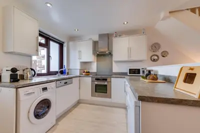 a kitchen with white cabinets and a washer and dryer at 2 Bed in Padstow oc-p00330 in Padstow