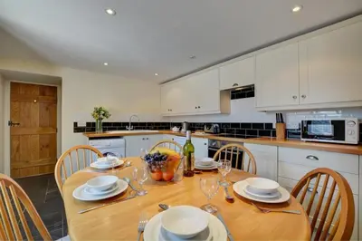 a kitchen with a wooden table with plates and wine glasses at 2 Bed in Padstow oc-p00282 in St Merryn