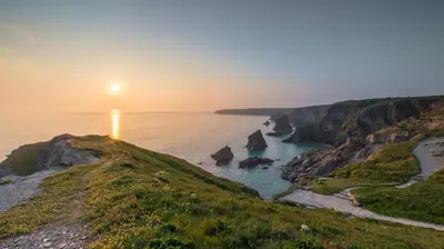 a sunset over the ocean with rocks in the water at 2 Bed in Newquay oc-p00335 in Mawgan Porth