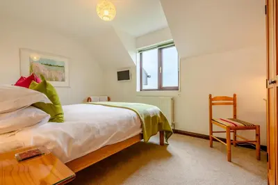 a bedroom with a bed and a chair and a window at 2 Bed in Padstow oc-p00385 in Padstow