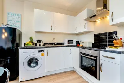 a kitchen with white cabinets and a washer and dryer at 2 Bed in Padstow oc-p00398 in St Merryn
