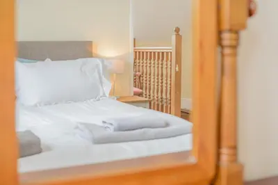 a mirror reflection of a bed with white sheets and pillows at 2 Bed in Padstow oc-p00398 in St Merryn