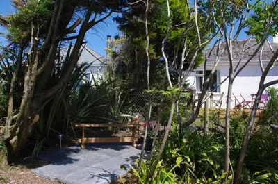 a wooden bench sitting in the middle of a garden at 2 Bed in Newquay oc-p00359 in Mawgan Porth