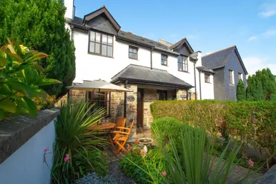 a large white house with a patio with chairs and an umbrella at 2 Bed in Padstow oc-p00424 in Padstow