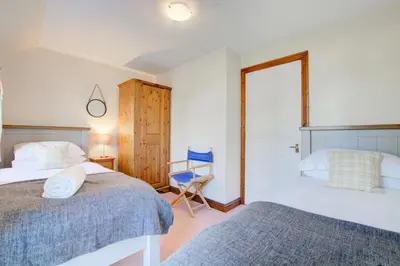 a bedroom with two beds and a blue chair at 2 Bed in Padstow oc-p00424 in Padstow