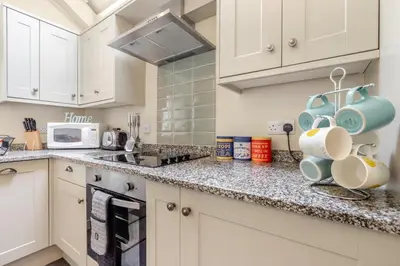 a kitchen with white cabinets and blue mugs on the counter at 2 Bed in Bodmin oc-p00405 in Bodmin