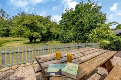 a wooden picnic table with a cake and two glasses of orange juice at 2 Bed in Bodmin oc-p00405 in Bodmin
