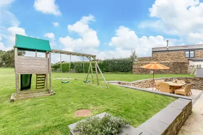 a playground with a swing in a yard at 3 Bed in Wadebridge oc-p00421 in Saint Issey