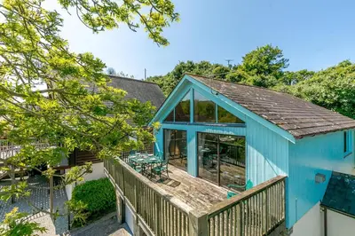 a blue house with a deck with a patio at 3 Bed in Wadebridge oc-p00427 in Little Petherick