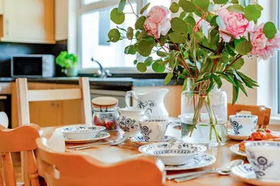 a table with a vase of pink flowers and dishes at 4 Bed in Padstow oc-p00401 in Padstow