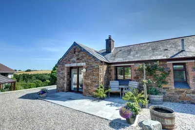 an exterior view of a brick house with a patio at 1 Bed in Wadebridge oc-p00440 in Saint Issey
