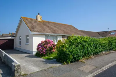 a white house with bushes and flowers in front of it at 2 Bed in Padstow oc-p00464 in St Merryn