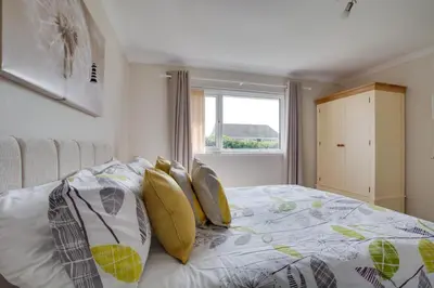a bedroom with a bed with yellow pillows and a window at 2 Bed in Padstow oc-p00464 in St Merryn
