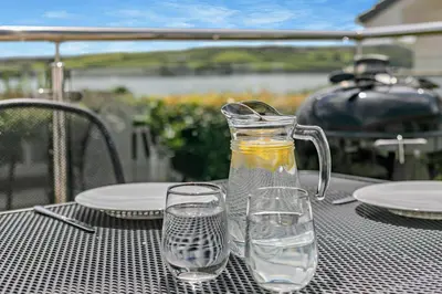a bottle of water and two glasses on a table at 3 Bed in Padstow oc-p00418 in Padstow