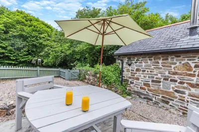a white table with an umbrella and two orange glasses at 1 Bed in Bodmin oc-p00438 in Bodmin