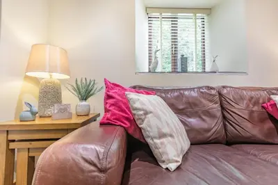 a brown leather couch with red and white pillows on it at 1 Bed in Bodmin oc-p00438 in Bodmin