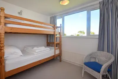 a bedroom with bunk beds and a chair and a window at 4 Bed in Padstow oc-p00425 in St Merryn