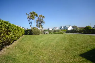 a large grassy yard with palm trees and houses at 4 Bed in Padstow oc-p00425 in St Merryn