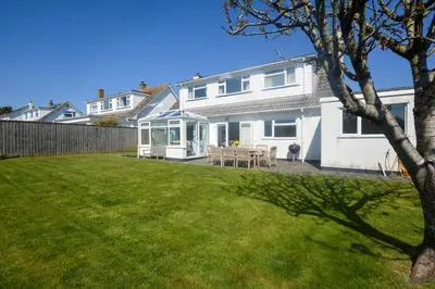 a white house with a lawn in front of it at 4 Bed in Padstow oc-p00425 in St Merryn