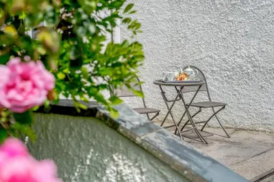 a small table with two chairs next to a wall at 1 Bed in Padstow oc-p00485 in St Merryn