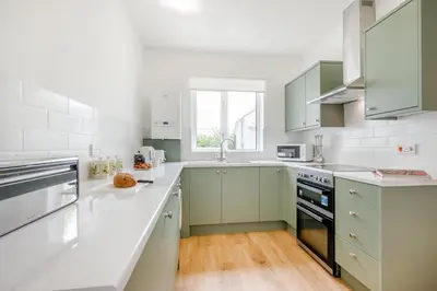 a white kitchen with green cabinets and a window at 1 Bed in Padstow oc-p00485 in St Merryn