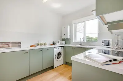 a kitchen with white cabinets and a washing machine at 1 Bed in Padstow oc-p00485 in St Merryn