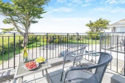 a balcony with two chairs and a table with a bowl of fruit at 2 Bed in Padstow oc-p00486 in St Merryn