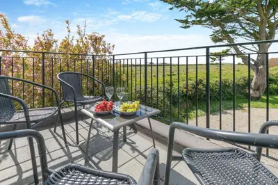 a table with wine glasses and fruit on a balcony at 2 Bed in Padstow oc-p00486 in St Merryn