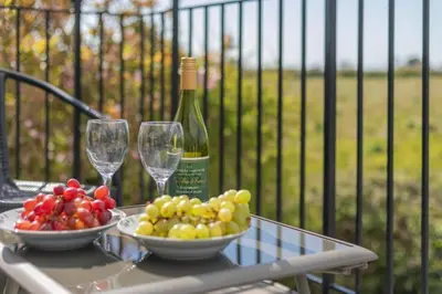 a table with a bottle of wine and bowls of fruit at 2 Bed in Padstow oc-p00486 in St Merryn