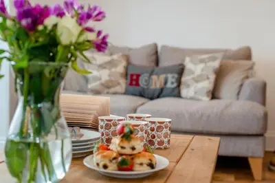 a table with a plate of food and a vase with flowers at 3 Bed in Padstow oc-p00455 in Padstow
