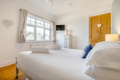 a white bedroom with two beds and a window at 3 Bed in Padstow oc-p00455 in Padstow