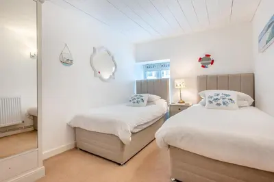 a bedroom with two beds and a mirror at 2 Bed in Padstow oc-p00505 in Padstow