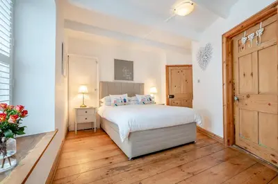 a bedroom with a white bed and a wooden floor at 2 Bed in Padstow oc-p00505 in Padstow