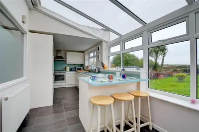 a kitchen with a counter with three stools in it at 4 Bed in Padstow oc-p00528 in Padstow