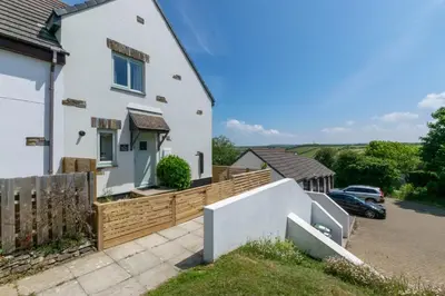 a white house with a wooden fence and a driveway at 2 Bed in Padstow oc-p00531 in Padstow