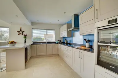 a large kitchen with white cabinets and blue walls at 6 Bed in Constantine Bay oc-p00571 in St Merryn
