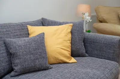 a gray couch with a yellow pillow on it at 6 Bed in Constantine Bay oc-p00571 in St Merryn