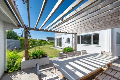 a patio with a wooden pergola and benches at 6 Bed in Constantine Bay oc-p00571 in St Merryn