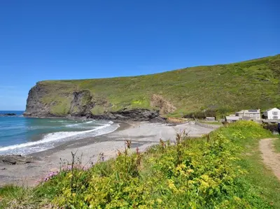 a beach with houses on a hill next to the ocean at 2 Bed in Crackington Haven oc-p00596 in Crackington Haven