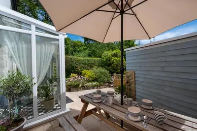 a patio with a wooden table and an umbrella at 2 Bed in Penzance oc-p00597 in Saint Erth