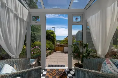 a conservatory with white curtains and chairs on a patio at 2 Bed in Penzance oc-p00597 in Saint Erth