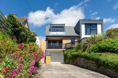 a house with a garage and some flowers at 4 Bed in Mawgan Porth oc-p00608 in Mawgan Porth