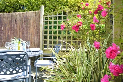 a table and chairs in a garden with pink flowers at 2 Bed in St. Merryn oc-p00607 in St Merryn